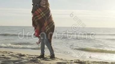 可爱的小男孩和他的母亲在海上。 有格子的女人拥抱她的儿子，手牵着手。 海滩上的幸福家庭。